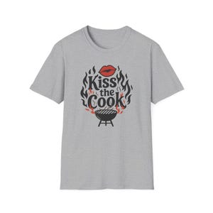 A gray t-shirt with a graphic design featuring a pair of lips and flames surrounding the text "Kiss the Cook".
