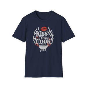 A navy blue t-shirt with a graphic design featuring a pair of lips and flames surrounding the text "Kiss the Cook".