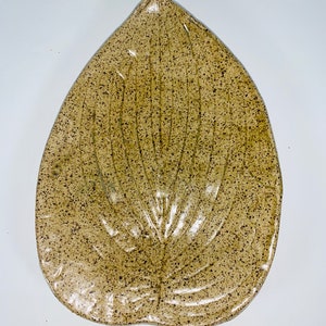May include: A ceramic leaf-shaped serving dish with a speckled brown and green glaze.