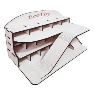 Peut inclure: Garage de voiture en bois pour jouet avec une rampe et plusieurs niveaux. Le garage est en bois clair et porte l'inscription "EcoToy" sur le devant.