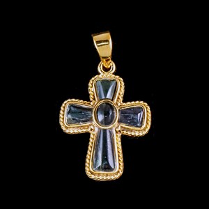 Può includere: Un ciondolo a forma di croce in oro con una pietra preziosa centrale blu scuro e pietre preziose blu più piccole intorno ai bordi.