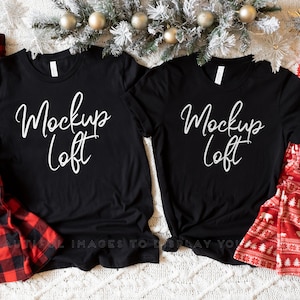 Pode incluir: Duas camisetas pretas com o texto "Mockup Loft" em letras brancas sobre um fundo branco. As camisetas estão dispostas lado a lado com um pijama xadrez vermelho e preto e um pijama vermelho e branco com uma caneca branca.