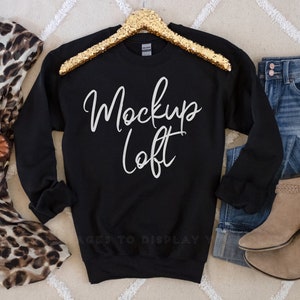 May include: Black sweatshirt with long sleeves and a crew neck. The sweatshirt has the text "Mockup Loft" written in white on the front.