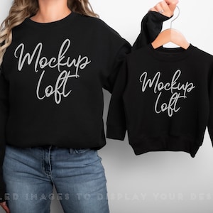 May include: Two black sweatshirts with the text "Mockup Loft" in white script. The larger sweatshirt is being worn by a person, while the smaller sweatshirt is hanging on a hanger.