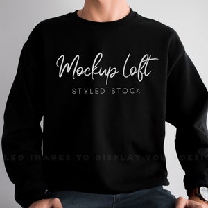 Könnte beinhalten: Schwarzes Sweatshirt mit Rundhalsausschnitt und dem weißen Schriftzug "Mockup Loft STYLED STOCK". Das Sweatshirt hat eine einfarbige schwarze Farbe und wird von einer Person getragen.