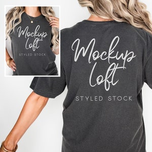 May include: A charcoal grey t-shirt with short sleeves and a crew neck. The shirt has the text "Mockup Loft" written in white on the back. The text "Styled Stock" is also written in white on the back of the shirt.