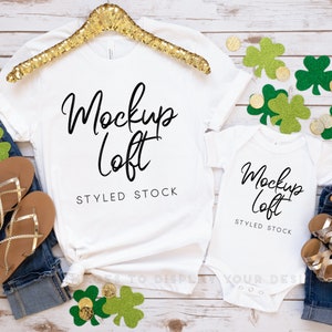 May include: White t-shirt and onesie mockup with the text "Mockup Loft" and "Styled Stock" on a white wood background with gold coins and green shamrocks.