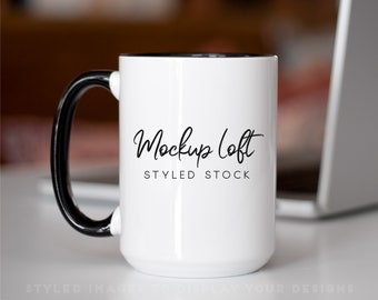 Może przedstawiać: Biały kubek ceramiczny z czarnym uchwytem i czarnym rantem. Kubek ma nadrukowany tekst "Mockup Loft Styled Stock" na przodzie.
