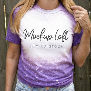 May include: A white and purple tie-dye t-shirt with the text "Mockup Loft Styled Stock" printed on the front.