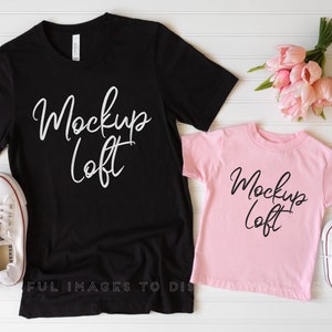 May include: Two black t-shirts with the text "Mockup Loft" in white lettering. The larger shirt is on a white surface with a pair of white sneakers. The smaller shirt is pink and is on a white surface with a pair of white sneakers and a bouquet of pink flowers.