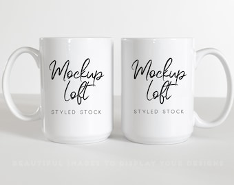 Puede incluir: Dos tazas de cerámica blanca con texto negro que dice "Mockup Loft STYLED STOCK".