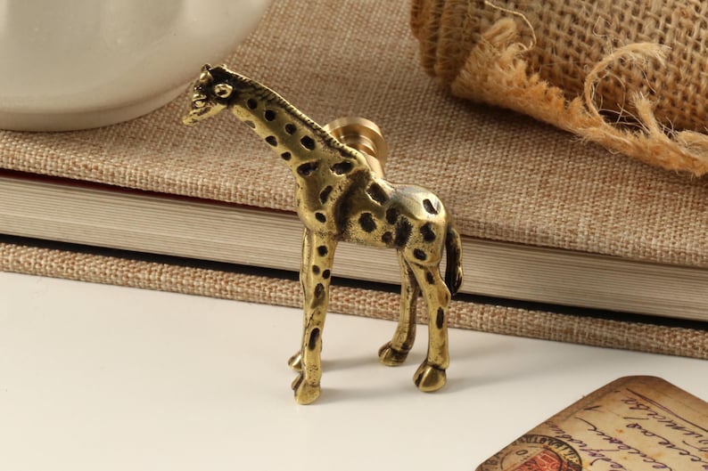 May include: A gold-toned giraffe figurine with a spotted pattern. The figurine is a decorative piece for a home or office.