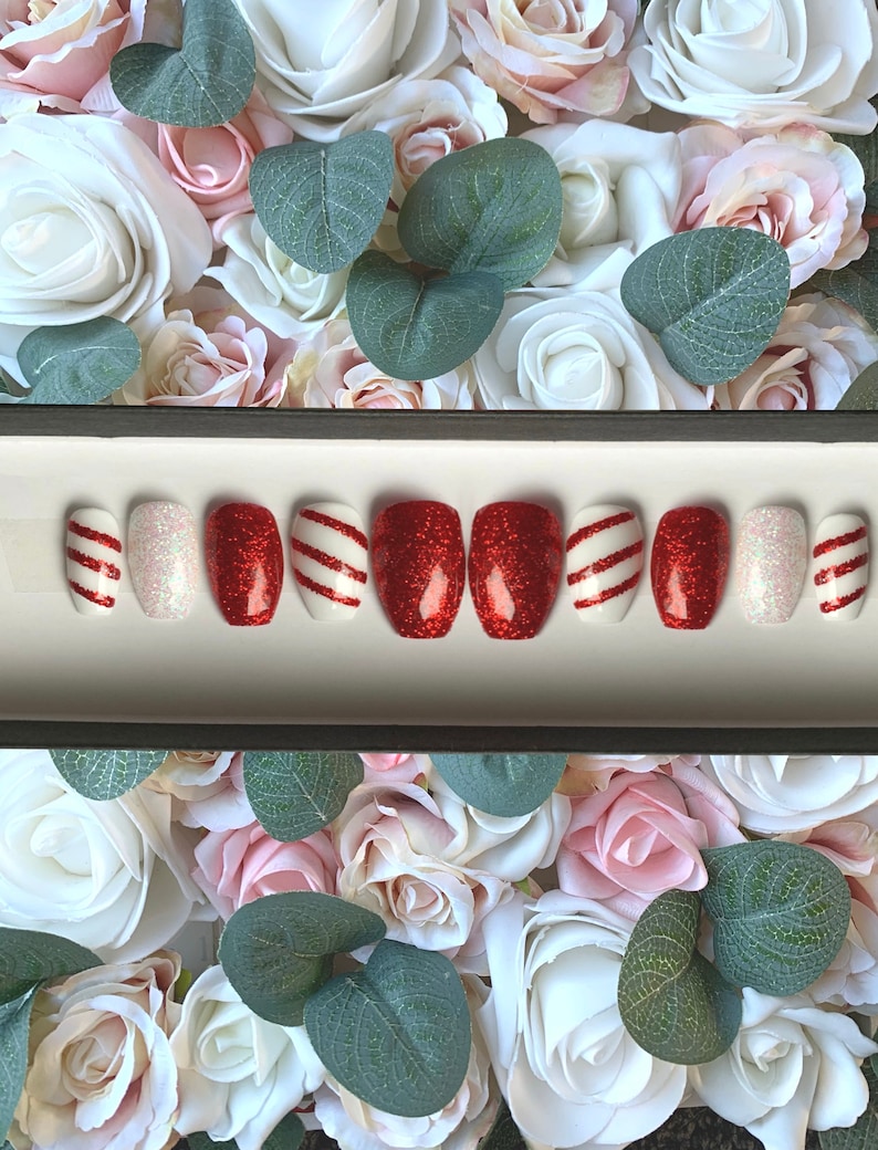 Puede incluir: Conjunto de diez u&ntilde;as postizas con un dise&ntilde;o de bast&oacute;n de caramelo rojo y blanco. Las u&ntilde;as son cortas y de forma ovalada. Algunas u&ntilde;as tienen un acabado brillante.