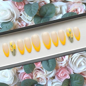 May include: A set of ten false nails with a yellow and white ombre design and a small floral design on one nail.