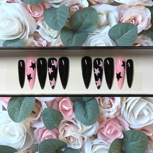 May include: A set of ten black stiletto false nails with pink and black star accents.