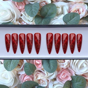 Könnte beinhalten: Set mit zehn roten Glitzer-Press-on-Nägeln in Sargform.