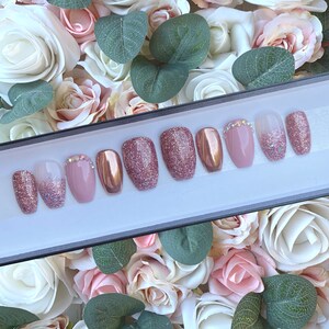 Pu&ograve; includere: Un set di dieci unghie finte in una variet&agrave; di stili. Le unghie sono rosa, glitter e oro rosa. Alcune unghie hanno strass.