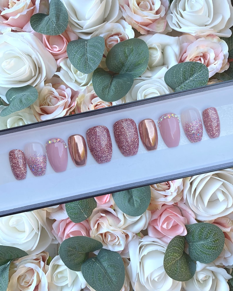 Pu&ograve; includere: Un set di dieci unghie finte in una variet&agrave; di stili. Le unghie sono rosa, glitter e oro rosa. Alcune unghie hanno strass.