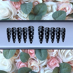 May include: Set of ten black stiletto false nails with white polka dots.