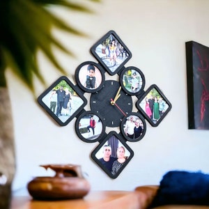 Può includere: Un orologio nero con quadrante bianco e lancette dorate. L'orologio è circondato da otto cornici nere con foto di persone.