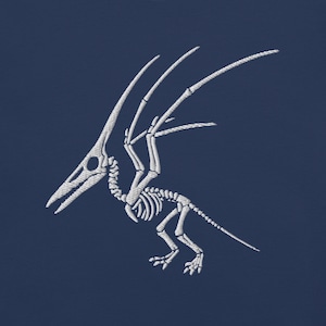 May include: White embroidered Pterodactyl skeleton design on a navy blue background. The prehistoric creature is depicted in profile, showcasing its skeletal structure. The design features detailed stitching, highlighting the bones and wings.