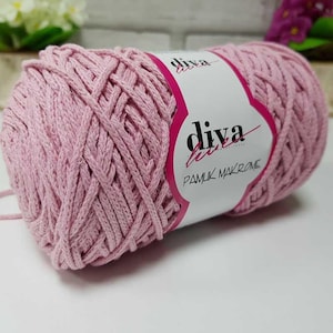 Puede incluir: Una bola de cordón de macramé de algodón rosa con una etiqueta blanca que dice "diva luxe pamuk makrome".