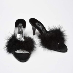 May include: Pair of black satin heeled slippers with black feather trim. The slippers have a pointed toe and a high heel. The brand name "G&C Collection" is printed on the side of the slippers.