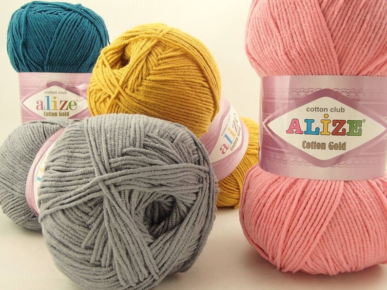 May include: Four balls of yarn in different colors: teal, yellow, gray, and pink. Each ball has a label that says "cotton club alize Cotton Gold".