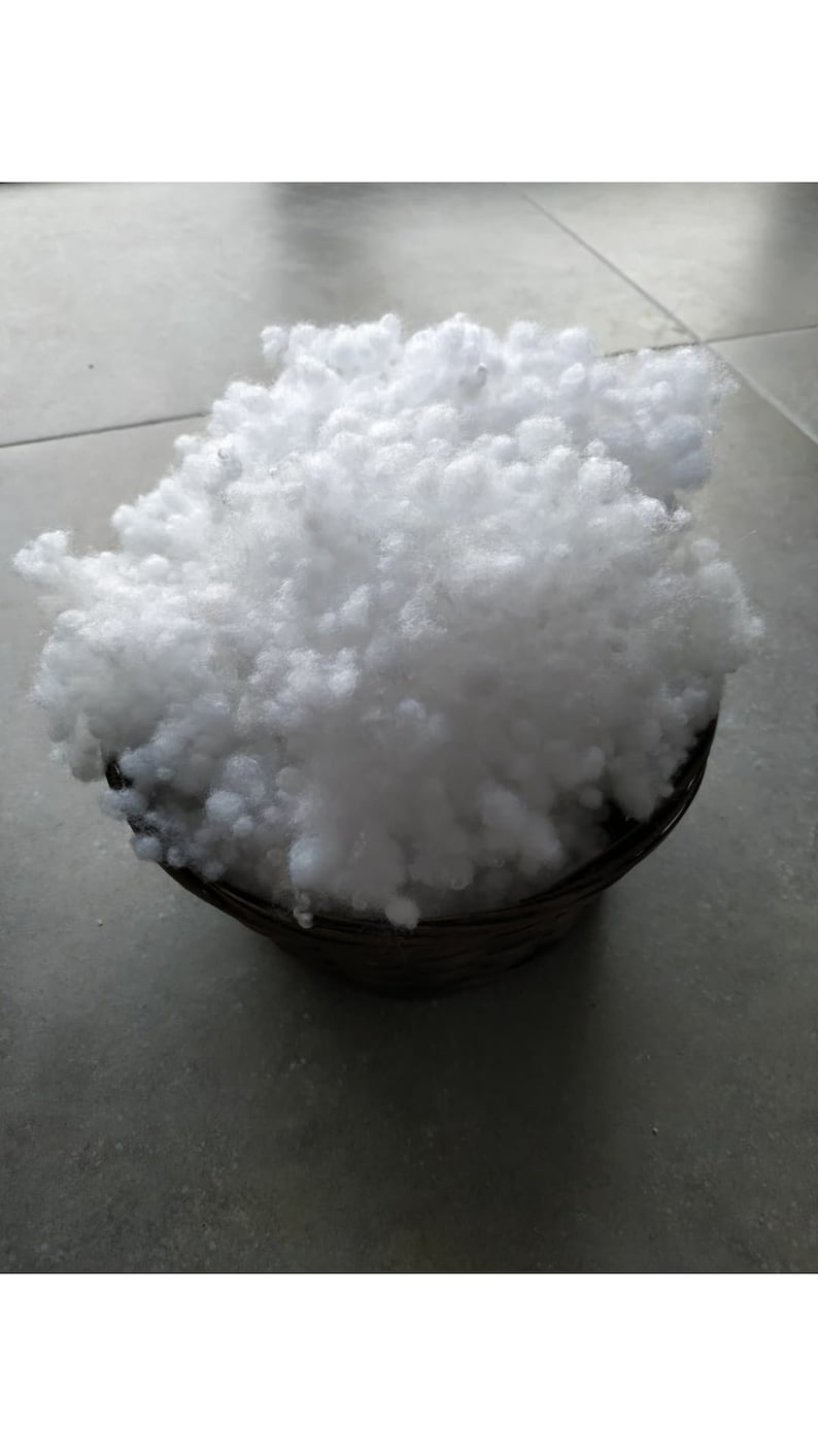 May include: A white, fluffy, polyester fiberfill in a brown basket. The fiberfill is used for stuffing pillows, cushions, and other home decor items.