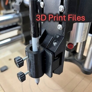 May include: A black 3D printed pen holder with two knobs for adjusting the pen height. The holder is attached to a black and silver machine with the text "3D Print Files" on it. A black and white pen is inserted into the holder.