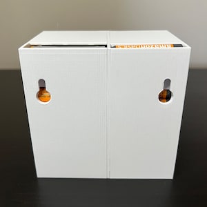 May include: Two white boxes with the text "AmazonBasics" printed on the top of one box. Each box has a small round hole on the front.