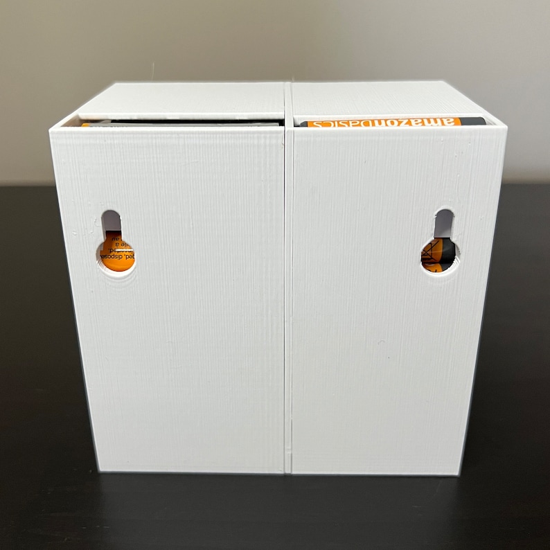 May include: Two white boxes with the text "AmazonBasics" printed on the top of one box. Each box has a small round hole on the front.