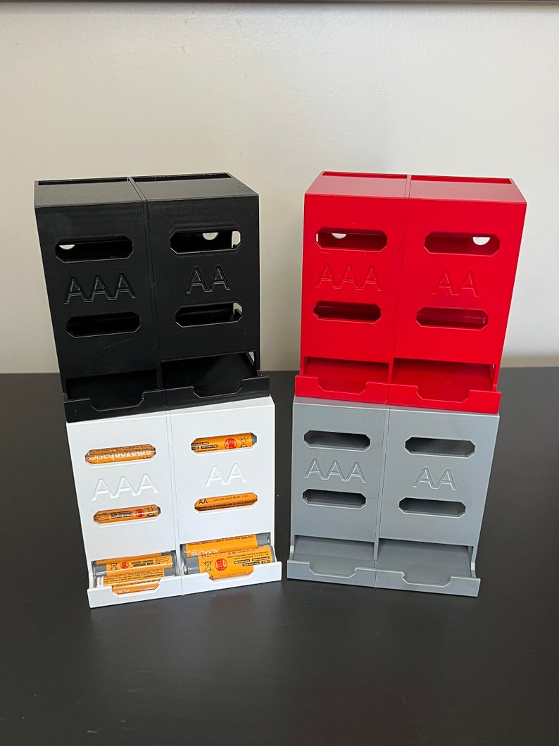 May include: Three sets of battery organizers, each with two compartments. The first set is black, the second is red, and the third is gray. Each compartment is labeled with "AAA" or "AA".