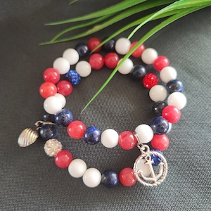 May include: Two bracelets with red, white and blue beads. One bracelet has a silver charm with an anchor. The other bracelet has a silver charm with a seashell.