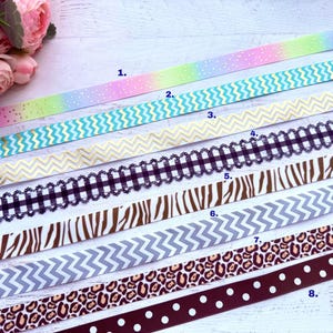 May include: An assortment of decorative ribbons in various patterns and colors. Designs include a pastel rainbow with gold dots, teal zigzags, gold chevrons, black and white gingham, zebra stripes, gray chevrons, leopard print, and a brown ribbon with white polka dots.