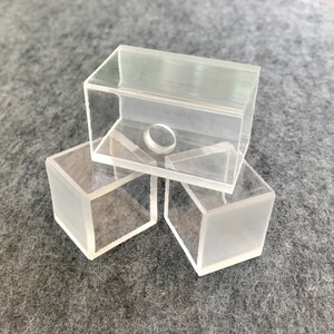 以下が含まれることがあります： 3つの透明なアクリルボックスが積み重ねられています。 上のボックスの中央に小さな丸い穴があります。