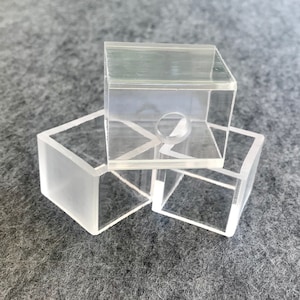 May include: Three clear acrylic boxes, one with a circular hole in the center, stacked on top of each other.