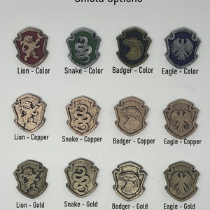 May include: Nine different shield designs, each featuring a different animal: a lion, a snake, a badger, and an eagle. Each animal is shown in three different finishes: colour, copper, and gold.
