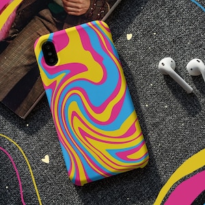 Könnte beinhalten: Eine Handyhülle mit einem wirbelnden abstrakten Design in Pink, Blau und Gelb. Die Hülle liegt auf einer grauen Oberfläche mit gelben, pinken und blauen Linien.
