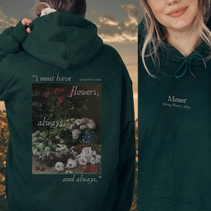 Könnte beinhalten: Ein dunkelgrüner Hoodie mit einem Zitat über Blumen und einem Blumenbild von Monet. Das Zitat lautet "Ich muss Blumen haben, immer und immer wieder."