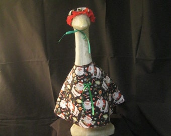 May include: A white goose figurine wearing a red and white Santa hat and a black and white Christmas-themed dress with a green ribbon.