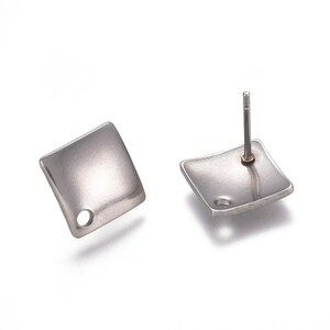 May include: A pair of silver square earring studs with a small hole in the centre of each square.