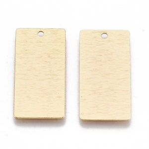 May include: Two gold-coloured rectangular metal tags with a hole at the top. The tags have a brushed finish.