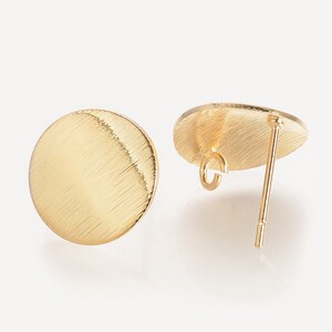 May include: A pair of gold-toned earring blanks with a brushed finish. The blanks are round and have a post and loop for attaching earrings.