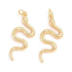 May include: Two gold snake charms with a textured surface and a single clear rhinestone for an eye. The charms have a loop at the top for attaching to a necklace or bracelet.