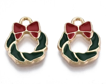May include: Two gold-colored metal charms shaped like Christmas wreaths with red bows. The wreaths are green with a gold outline.
