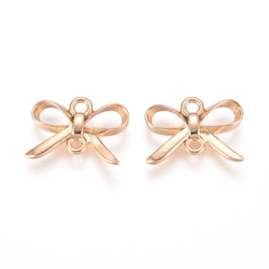 May include: Two gold-toned metal bow charms with a loop at the top for attaching to jewellery or other crafts.