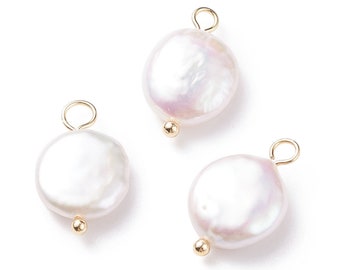 May include: Three white pearl charms with gold jump rings and gold balls at the bottom. The pearls are round and have a slight iridescent sheen.