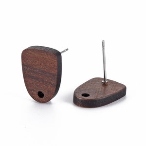 May include: Two wooden stud earrings. Each earring is a dark brown, shield-shaped piece of wood with a silver post. A small hole is drilled at the bottom of each earring. The earrings are set against a white background.