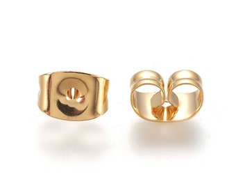 May include: Gold-toned earring backs, shown from the front and back. The backs are designed to fit over the post of an earring.